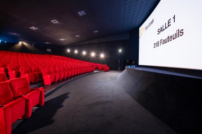 Salle de cinéma avec des rangées de fauteuils rouges et un écran affichant ’Salle 1, 318 fauteuils’.