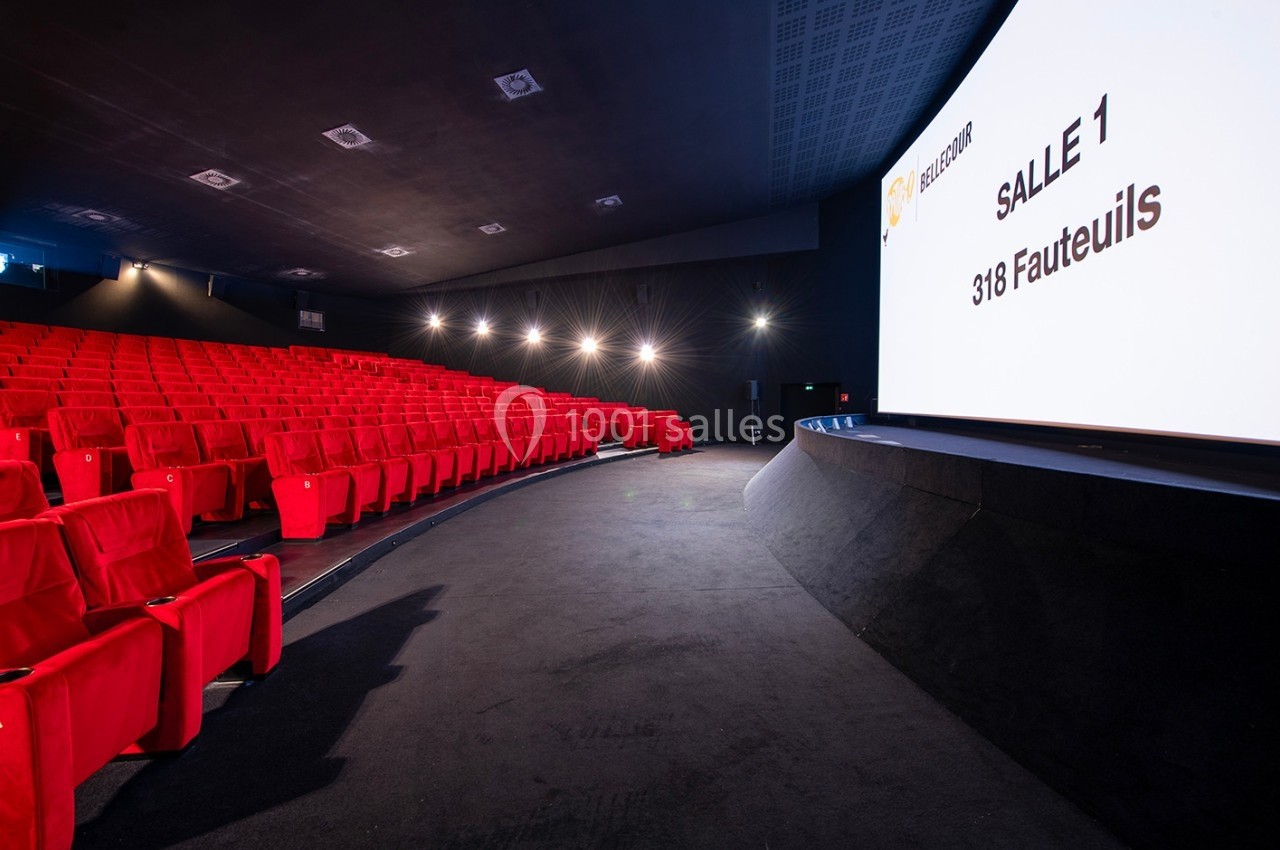 Salle de cinéma moderne avec des rangées de sièges rouges et un écran affichant ’Salle 1, 318 fauteuils’.