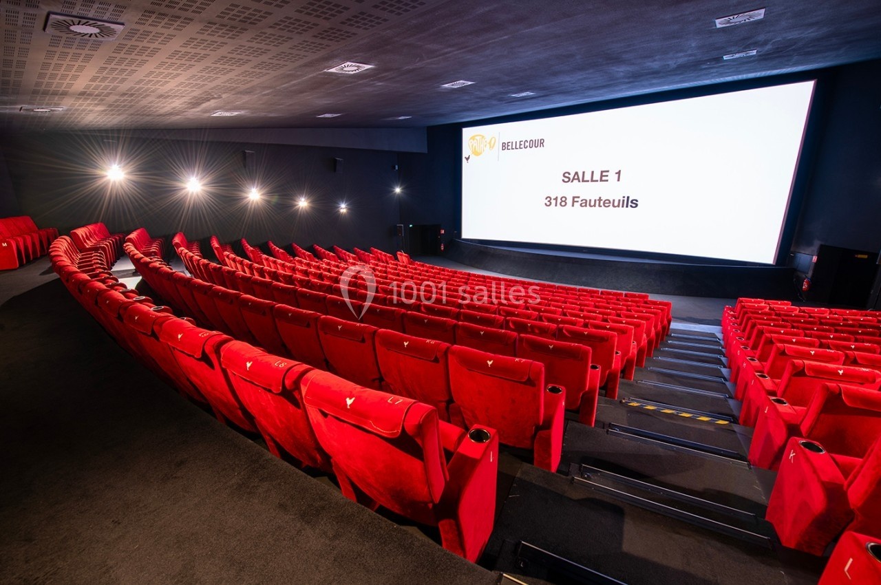 Salle de cinéma avec des rangées de fauteuils rouges et un écran affichant ’Salle 1, 318 fauteuils’.