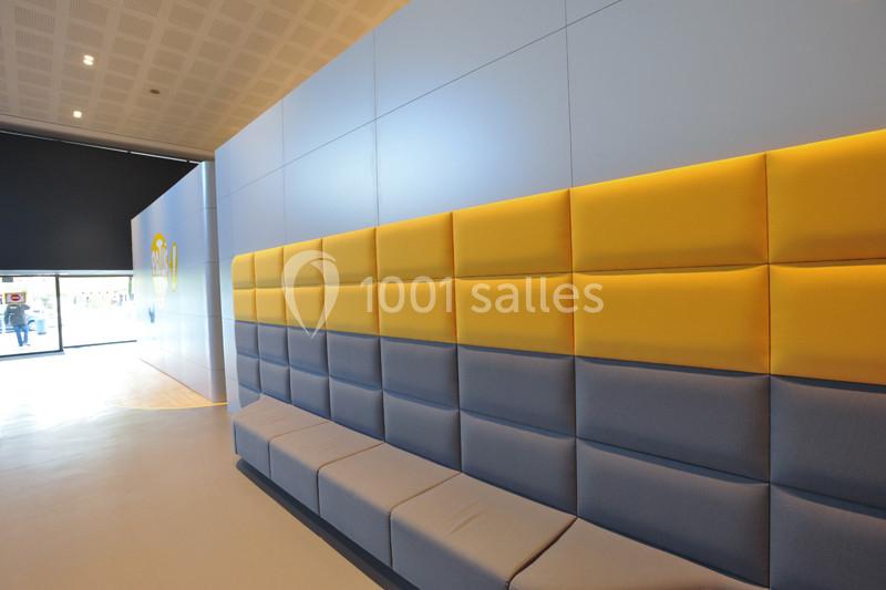 Banquette rembourrée en tissu jaune et gris le long d'un mur dans un espace intérieur lumineux.
