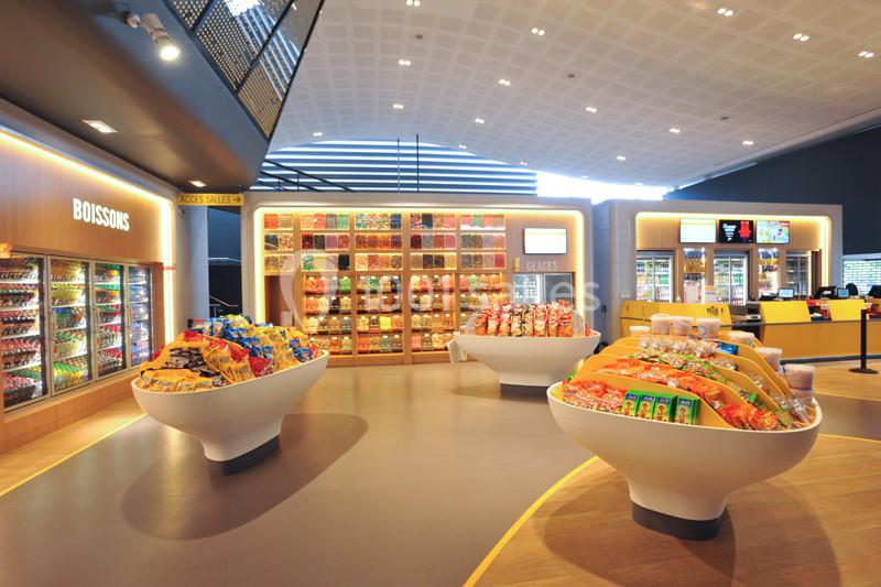 Rayons d'un espace de vente proposant boissons, confiseries et snacks dans un cadre lumineux et moderne.