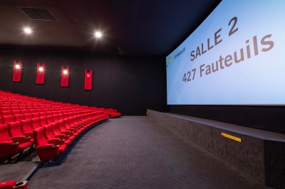 Couloir moderne avec éclairage tamisé, sièges incurvés, distributeurs automatiques et écrans muraux.