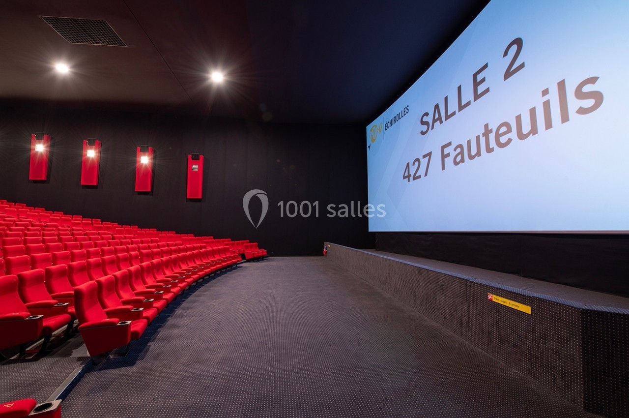 Salle de cinéma moderne avec des rangées de fauteuils rouges et un écran affichant ’Salle 2, 427 fauteuils’.