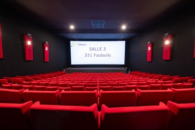 Couloir moderne avec éclairage tamisé, sièges incurvés, distributeurs automatiques et écrans muraux.