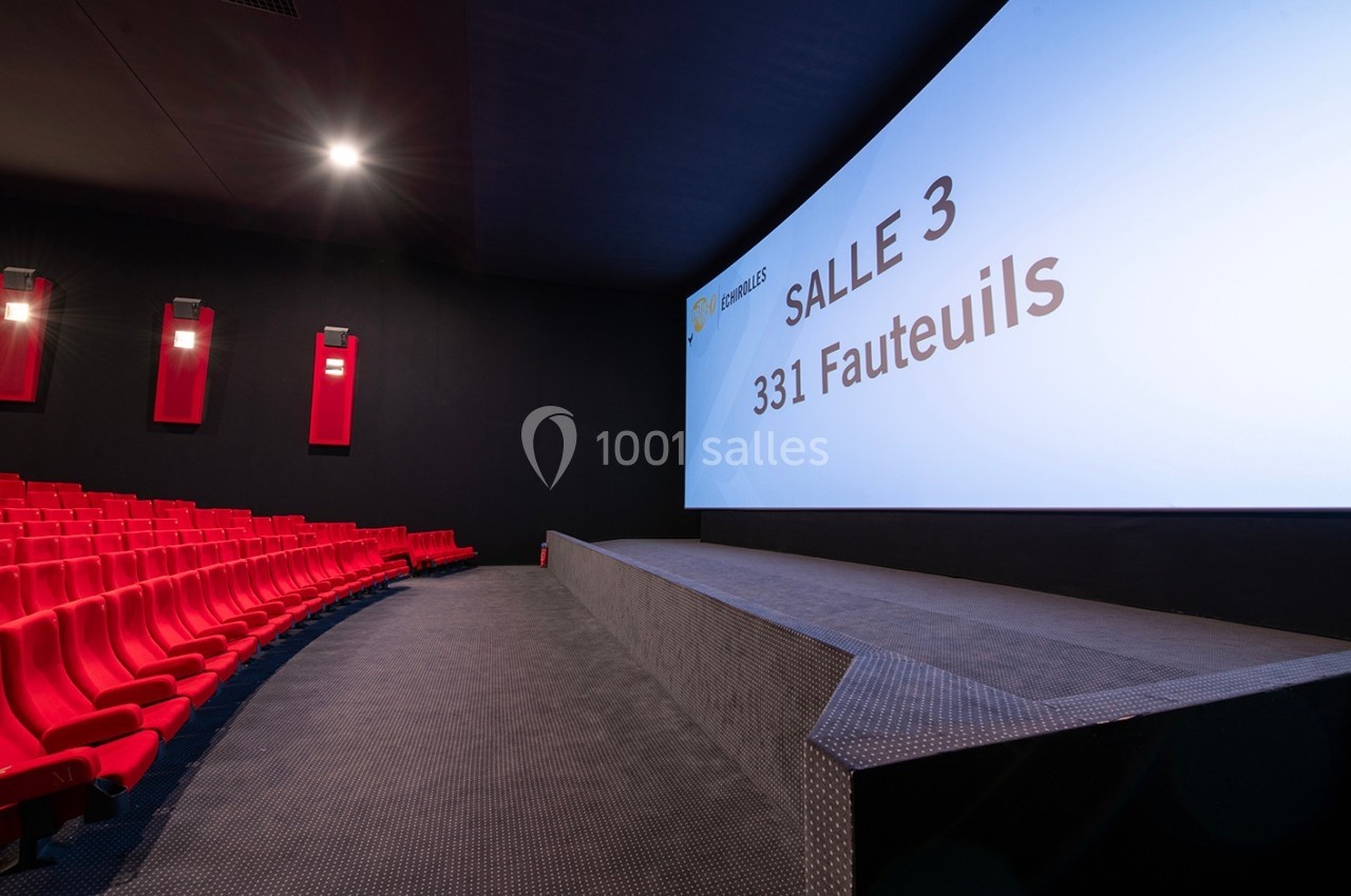 Salle de cinéma moderne avec sièges rouges, grand écran affichant ’Salle 3, 331 fauteuils’ et éclairage tamisé.