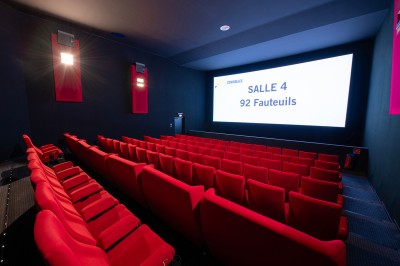 Couloir moderne avec éclairage tamisé, sièges incurvés, distributeurs automatiques et écrans muraux.