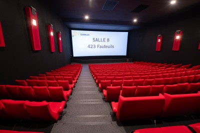 Couloir moderne avec éclairage tamisé, sièges incurvés, distributeurs automatiques et écrans muraux.