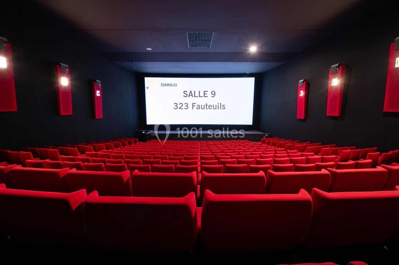 Salle de cinéma vide avec des rangées de fauteuils rouges et un écran affichant ’Salle 9, 323 fauteuils’.