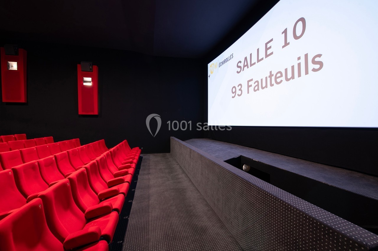 Salle de cinéma vide avec des fauteuils rouges et un écran affichant ’Salle 10, 93 fauteuils’.