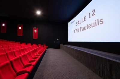 Couloir moderne avec éclairage tamisé, sièges incurvés, distributeurs automatiques et écrans muraux.