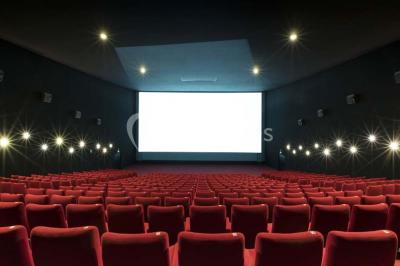 Façade d'un cinéma Pathé avec affiches de films en vitrine, sous un ciel bleu clair.