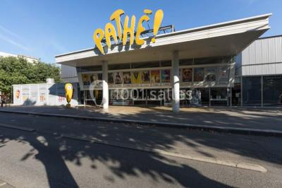 Façade d'un cinéma Pathé avec affiches de films en vitrine, sous un ciel bleu clair.