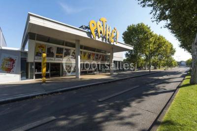 Façade d'un cinéma Pathé avec affiches de films en vitrine, sous un ciel bleu clair.