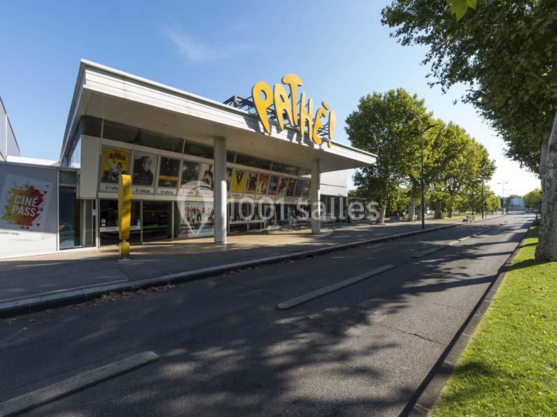 Façade d'un cinéma Pathé avec affiches de films, situé le long d'une rue bordée d'arbres.