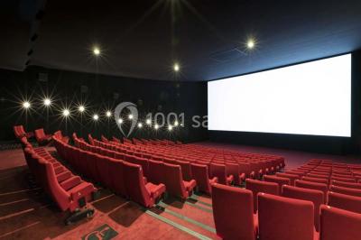 Façade d'un cinéma Pathé avec affiches de films en vitrine, sous un ciel bleu clair.
