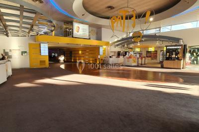 Façade d'un cinéma Pathé avec affiches de films en vitrine, sous un ciel bleu clair.
