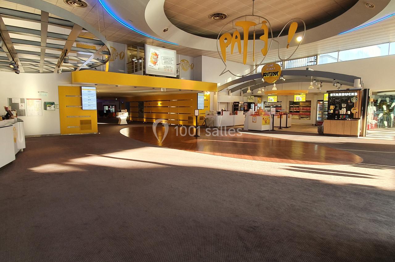 Hall d'entrée lumineux avec comptoirs d'accueil, enseignes de restauration et espace ouvert.