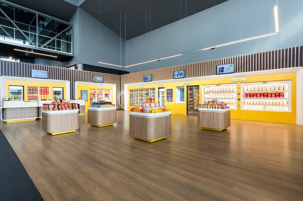 Rayons de snacks et boissons dans un espace lumineux avec présentoirs en bois et éclairage moderne.