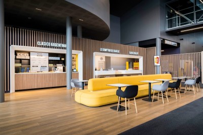 Salle de cinéma moderne avec des rangées de sièges rouges et un grand écran blanc allumé.