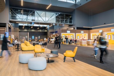Salle de cinéma moderne avec des rangées de sièges rouges et un grand écran blanc allumé.