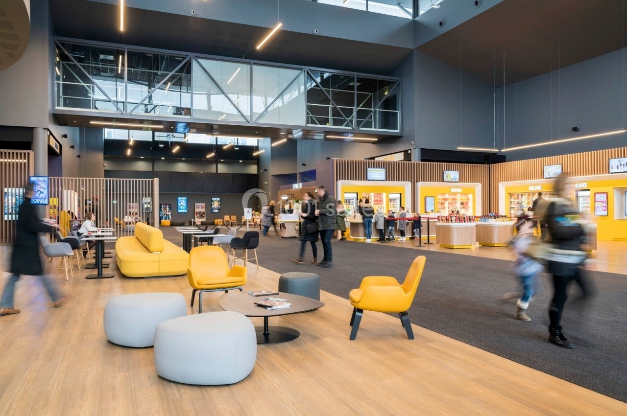 Hall lumineux avec sièges modernes, comptoirs de restauration et visiteurs en mouvement dans un espace public.