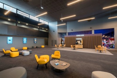 Salle de cinéma moderne avec des rangées de sièges rouges et un grand écran blanc allumé.