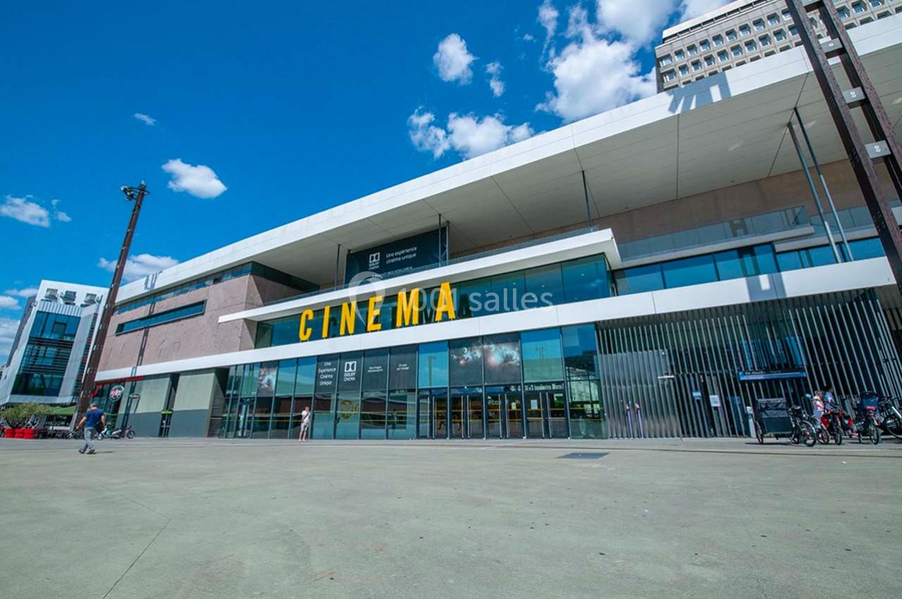 Façade moderne d'un cinéma avec une large entrée vitrée et des lettres jaunes indiquant ’CINEMA’.