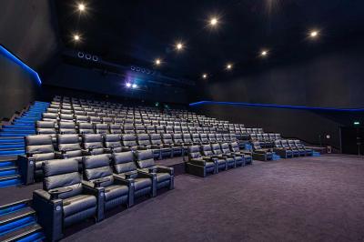Salle lumineuse avec murs jaunes et gris, mobilier moderne espacé, grandes fenêtres laissant entrer la lumière naturelle.