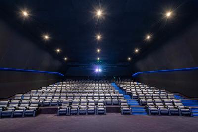 Salle lumineuse avec murs jaunes et gris, mobilier moderne espacé, grandes fenêtres laissant entrer la lumière naturelle.