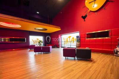 Salle de cinéma vide avec des rangées de fauteuils rouges et un éclairage tamisé.