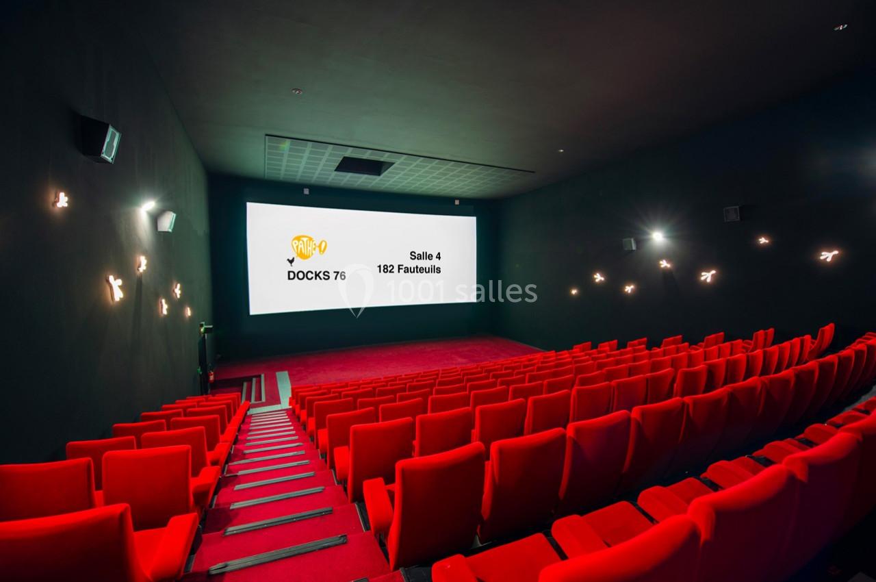 Salle de cinéma vide avec des rangées de sièges rouges et un écran affichant des informations sur la salle.