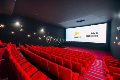 Salle de cinéma vide avec des rangées de fauteuils rouges et un éclairage tamisé.