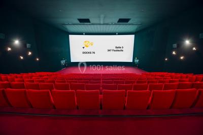 Salle de cinéma vide avec des rangées de fauteuils rouges et un éclairage tamisé.