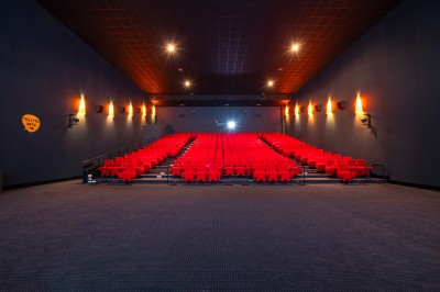 Entrée d'un cinéma Pathé avec affiches de films, sol violet, comptoirs de snacks et accès aux salles.