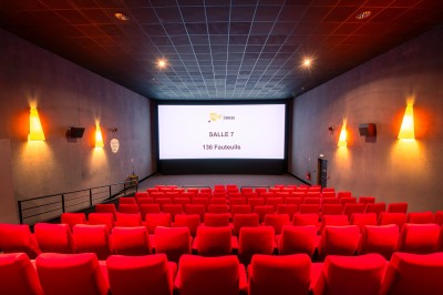 Entrée d'un cinéma Pathé avec affiches de films, sol violet, comptoirs de snacks et accès aux salles.