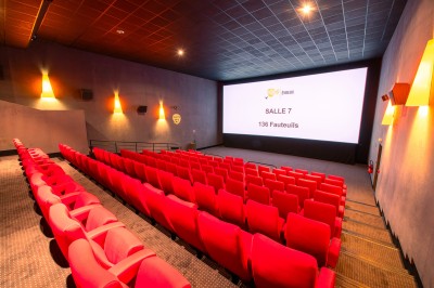 Entrée d'un cinéma Pathé avec affiches de films, sol violet, comptoirs de snacks et accès aux salles.