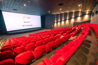 Entrée d'un cinéma Pathé avec affiches de films, sol violet, comptoirs de snacks et accès aux salles.