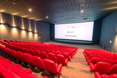 Entrée d'un cinéma Pathé avec affiches de films, sol violet, comptoirs de snacks et accès aux salles.
