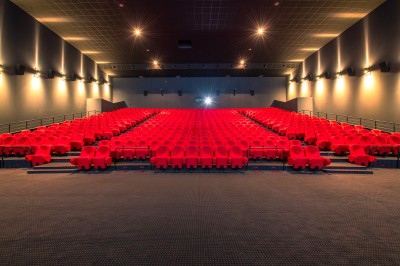 Entrée d'un cinéma Pathé avec affiches de films, sol violet, comptoirs de snacks et accès aux salles.