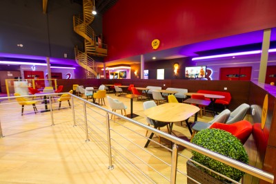 Entrée d'un cinéma Pathé avec affiches de films, sol violet, comptoirs de snacks et accès aux salles.