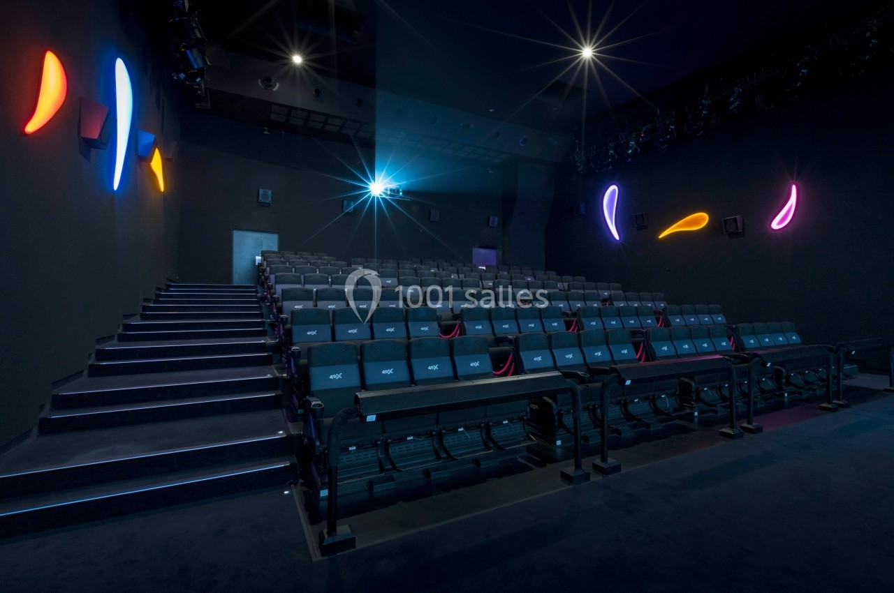 Salle de cinéma vide avec sièges alignés, éclairage tamisé et décorations lumineuses colorées sur les murs.