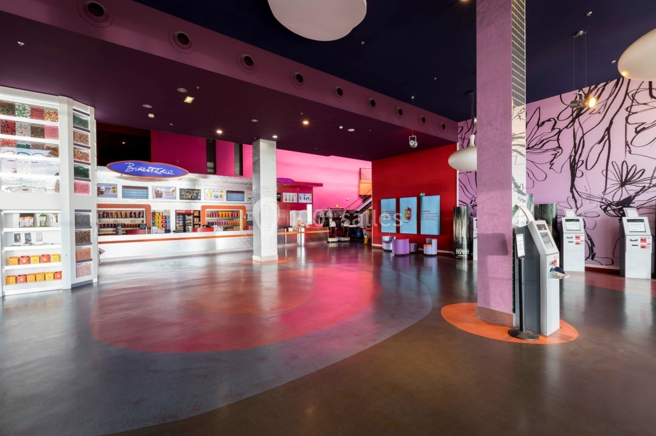 Intérieur d'un espace moderne avec comptoirs, bornes interactives et décorations murales colorées.