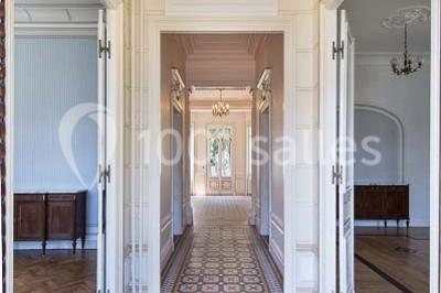 Cuisine vide avec carrelage beige, évier mural, étagères blanches, réfrigérateur et porte au fond.