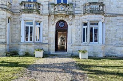 Cuisine vide avec carrelage beige, évier mural, étagères blanches, réfrigérateur et porte au fond.