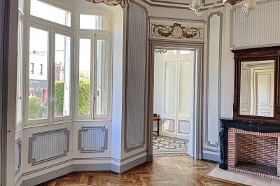 Cuisine vide avec carrelage beige, évier mural, étagères blanches, réfrigérateur et porte au fond.