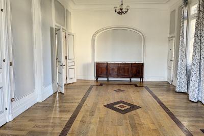 Cuisine vide avec carrelage beige, évier mural, étagères blanches, réfrigérateur et porte au fond.