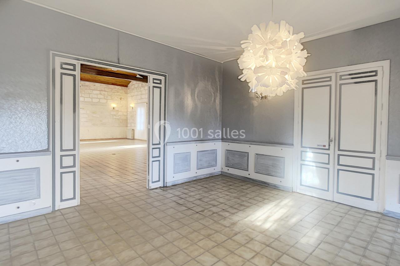 Salle lumineuse avec carrelage clair, murs gris texturés, portes blanches et lustre moderne en forme de pétales.