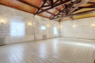 Cuisine vide avec carrelage beige, évier mural, étagères blanches, réfrigérateur et porte au fond.