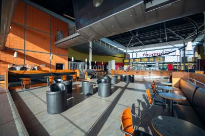 Salle de cinéma vide avec fauteuils rouges, grand écran allumé et plafond illuminé par des motifs lumineux.
