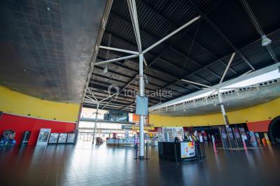 Salle de cinéma vide avec fauteuils rouges, grand écran allumé et plafond illuminé par des motifs lumineux.